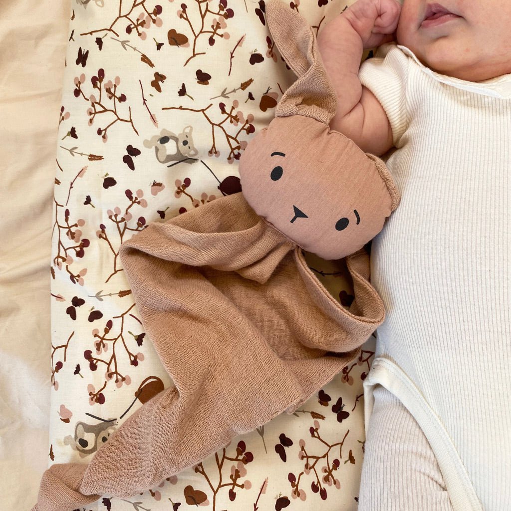 Baby slaapt met Nuuroo knuffeldoekje in roze tinten – sfeerbeeld