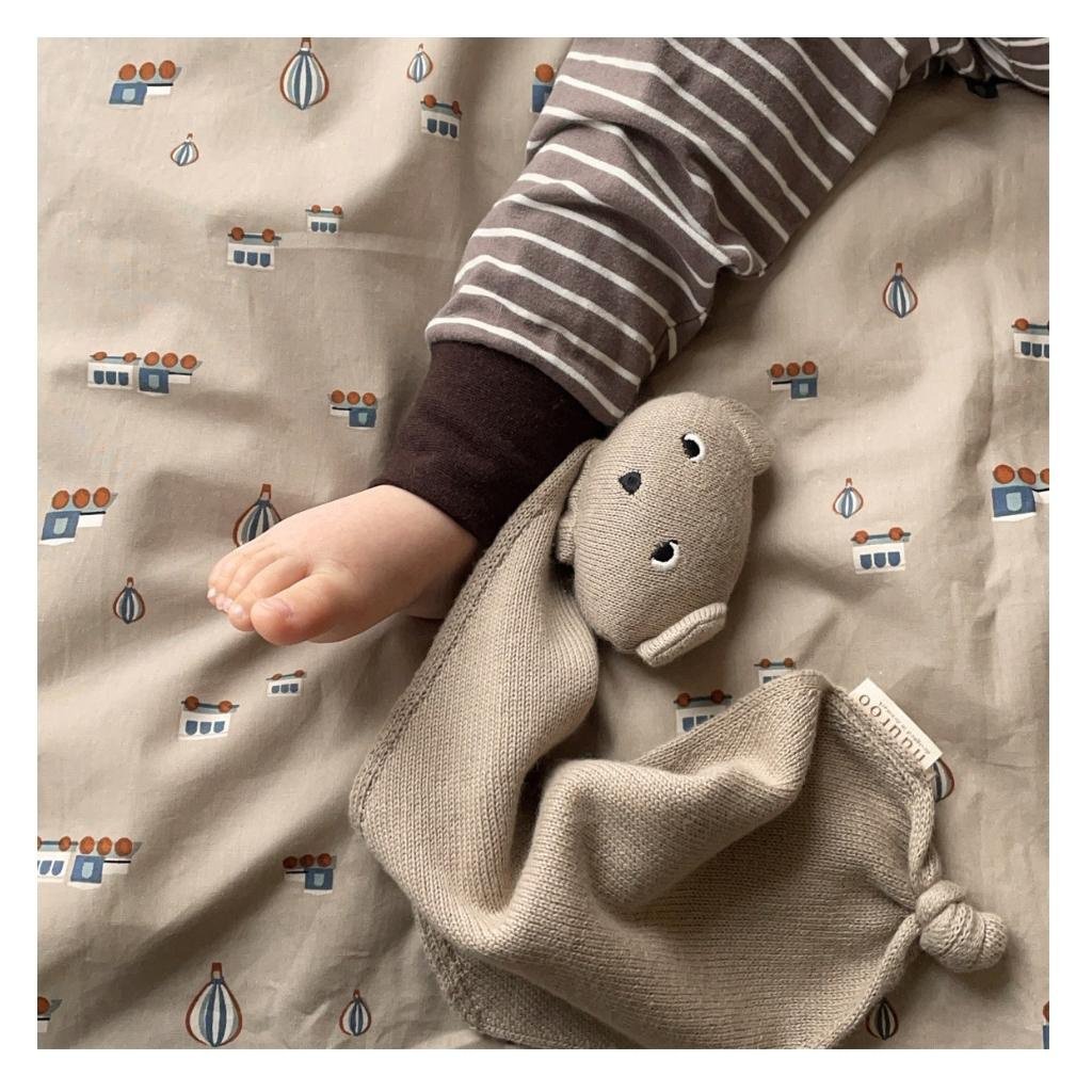 Baby speelt met zacht biologisch knuffeldoekje in warme tinten