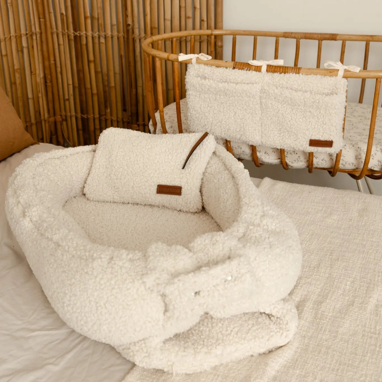 Babynestje teddy cream samen met luieretui en  crib organizer cream aan een wieg.