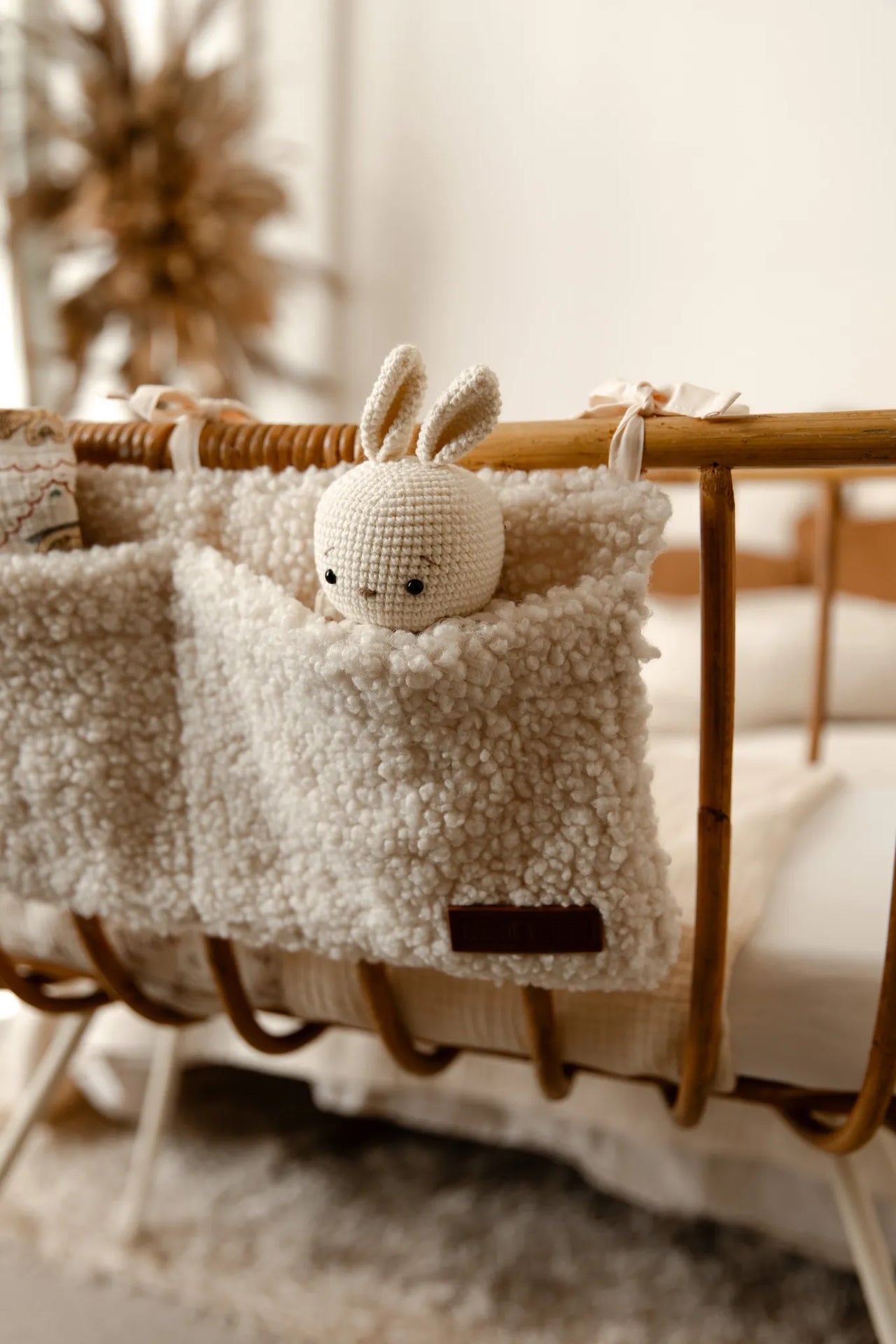 Close-up van crib organizer teddy cream met knuffel in de pocket aan een wieg.