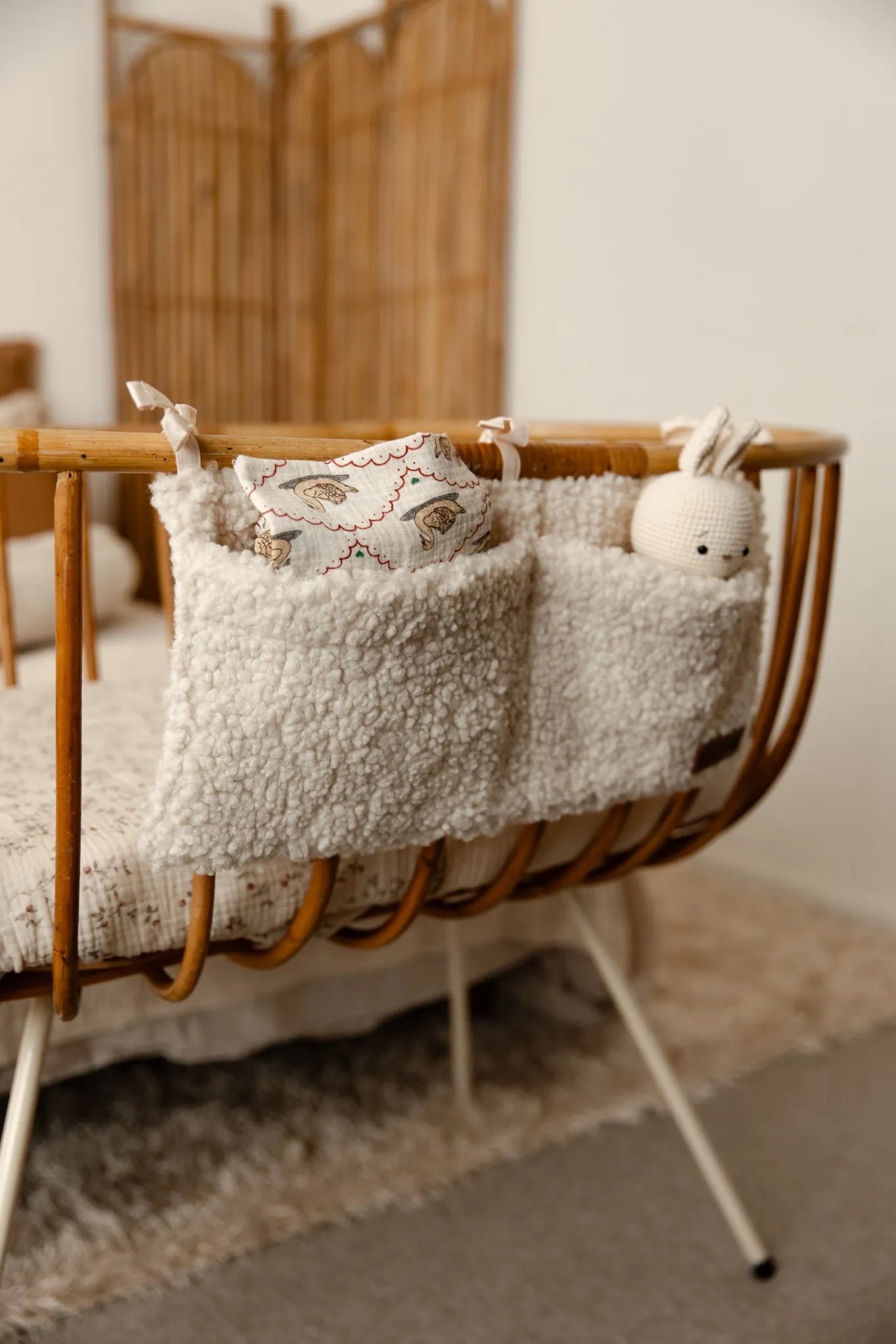 Crib organizer teddy cream gevuld met hydrofiele doek en knuffel konijn aan een wieg.