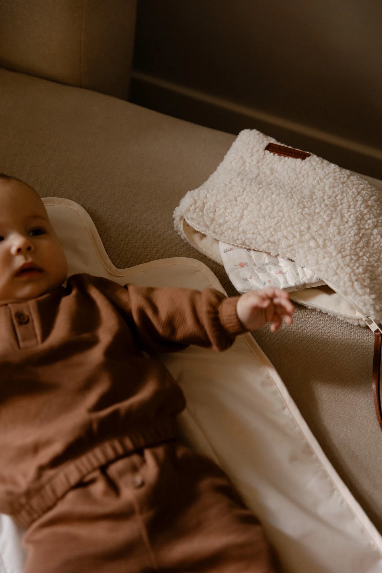 Baby ligt op verschoonmat naast Luieretui Teddy Cream