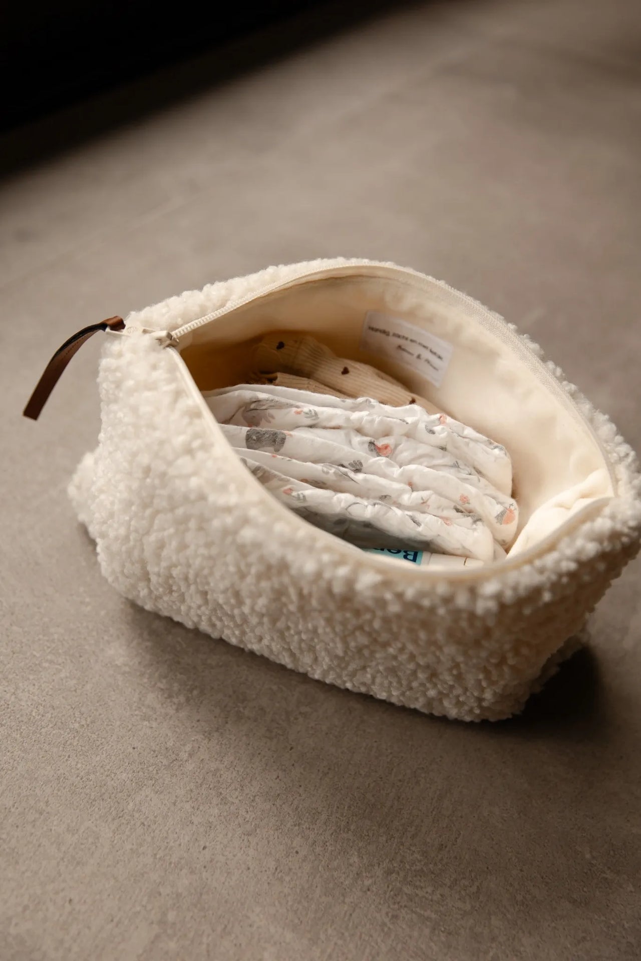 Luieretui teddy cream geopend met luiers en baby essentials zichtbaar.