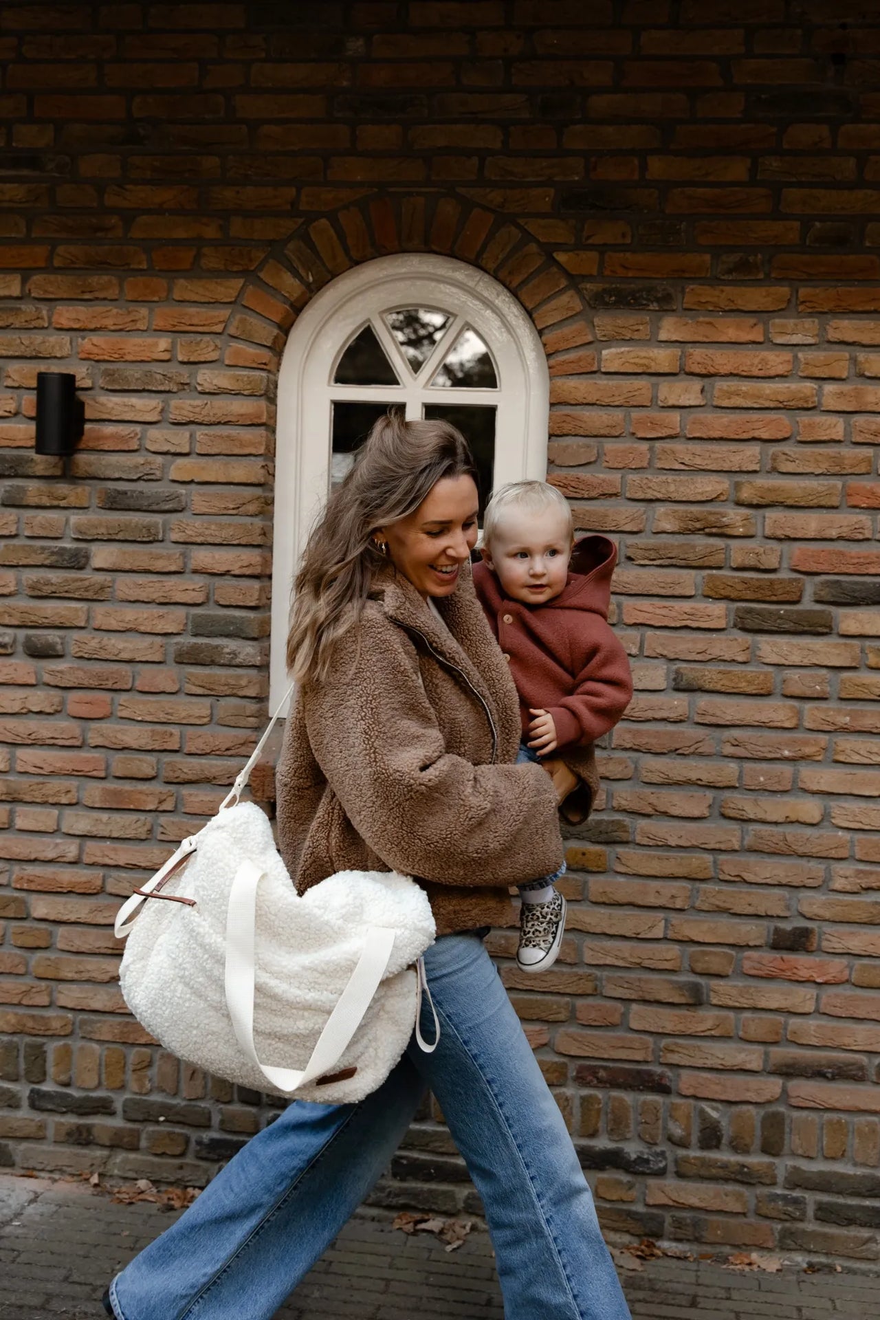 Moeder draagt de Benni & Ninni On-the-Go set luiertas met kind op de arm.