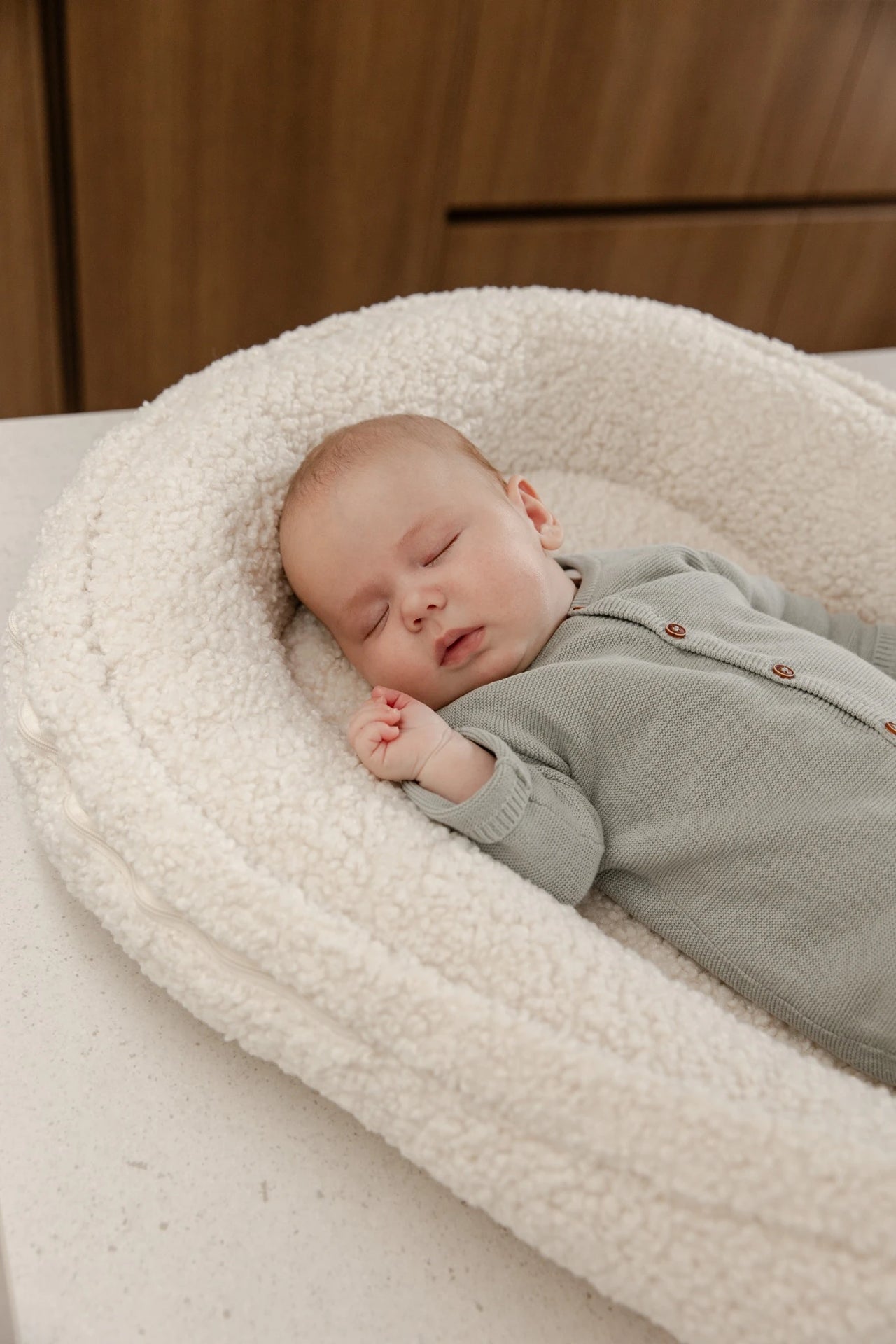 Slapende baby in een warm teddy babynest.