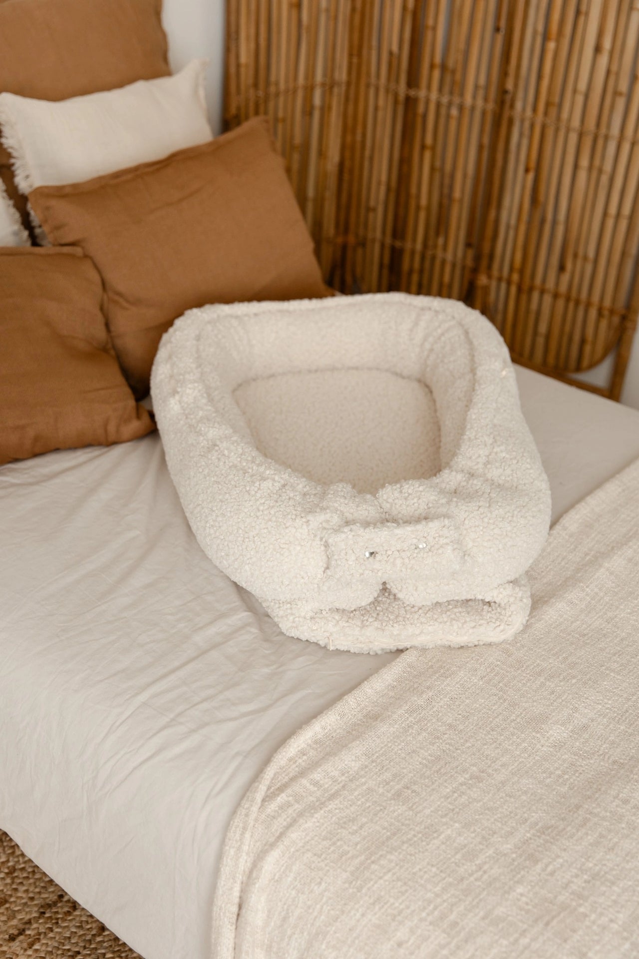 Teddy babynest cream netjes opgemaakt op een bed