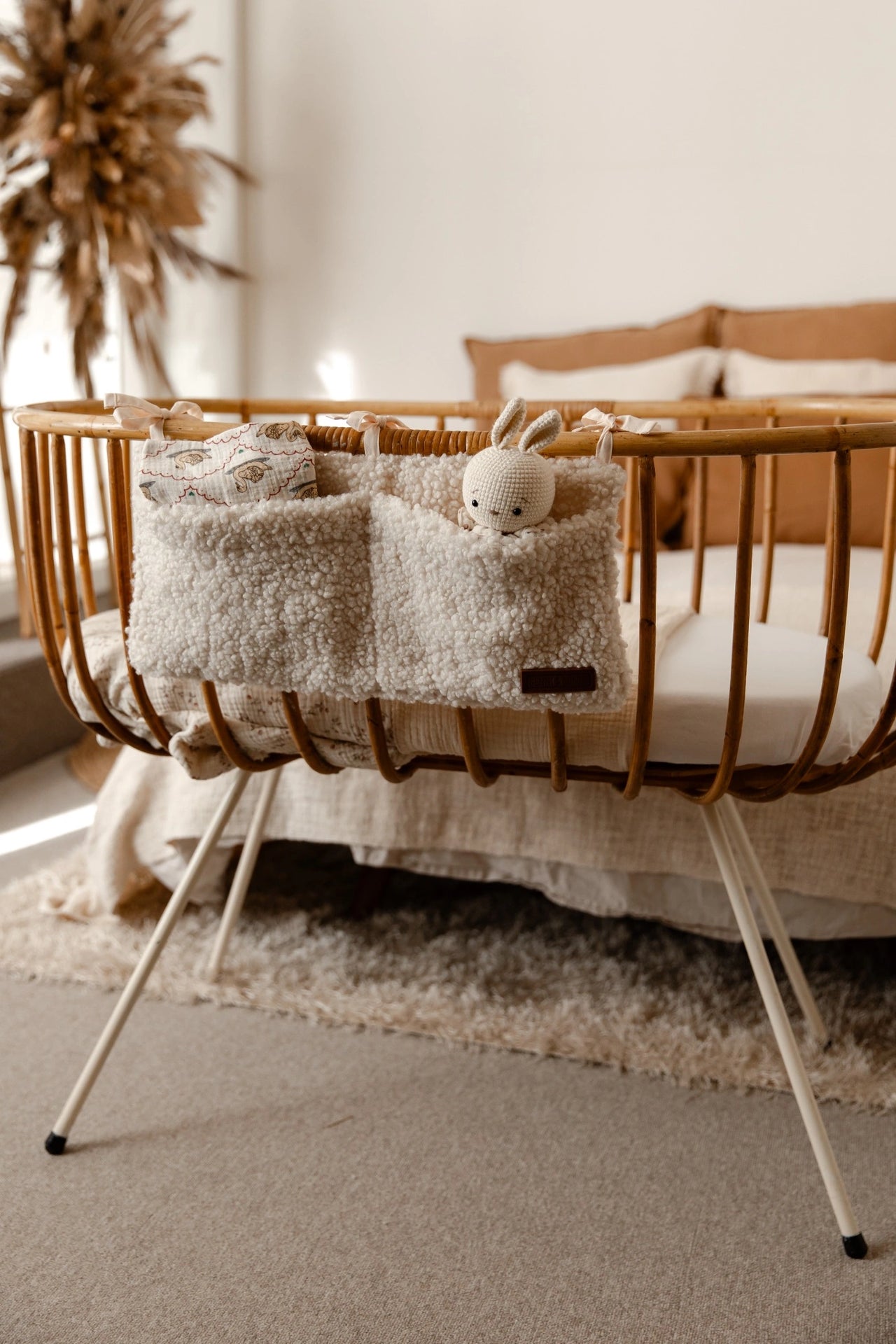 Teddy crib organizer cream gevuld met knuffel en doekje aan een wieg