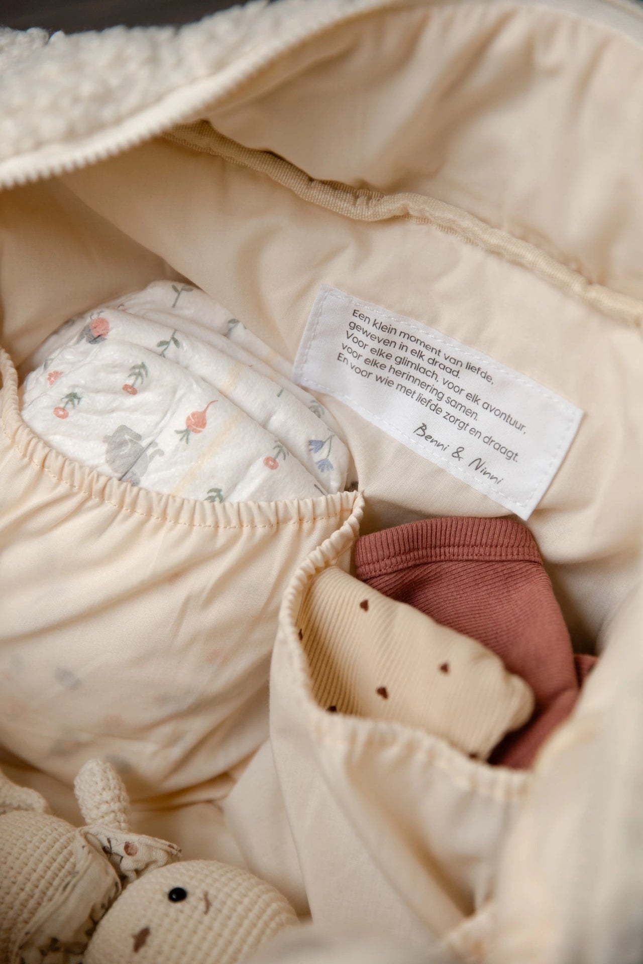 Detail van binnenkant teddy luiertas cream met luiers en kleding