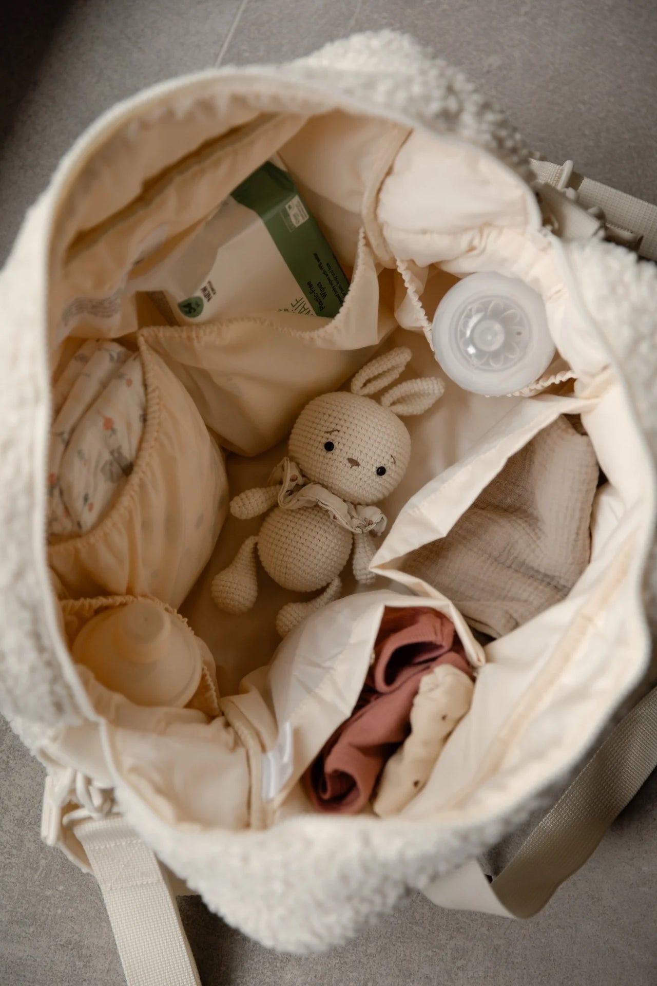 Teddy luiertas cream gevuld met babyflesjes, knuffel en kleding