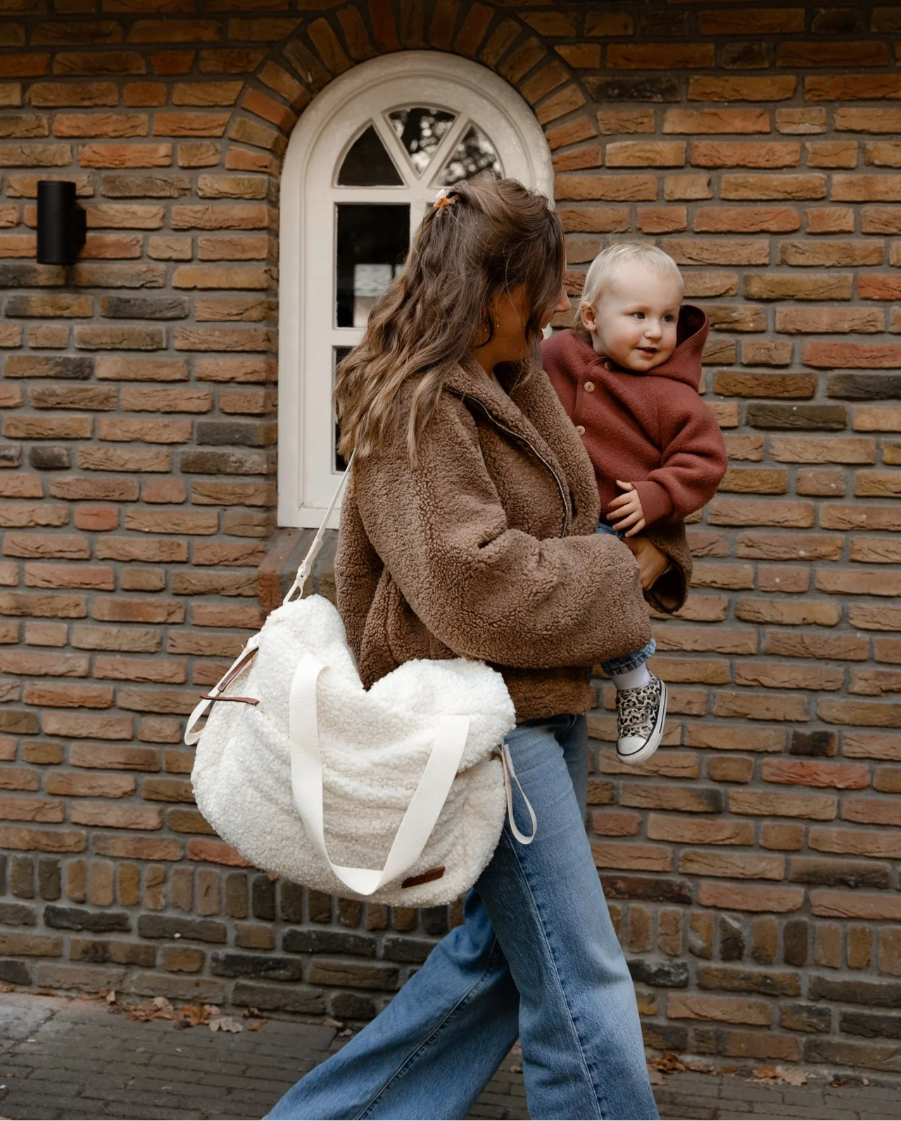 Moeder draagt teddy luiertas cream van Benni & Ninni met kindje op de arm